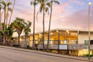 The front of Medical Hill with palm trees and a sunset