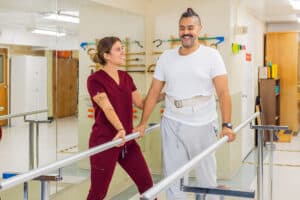 A physical therapist helping a man walk at Medical Hill