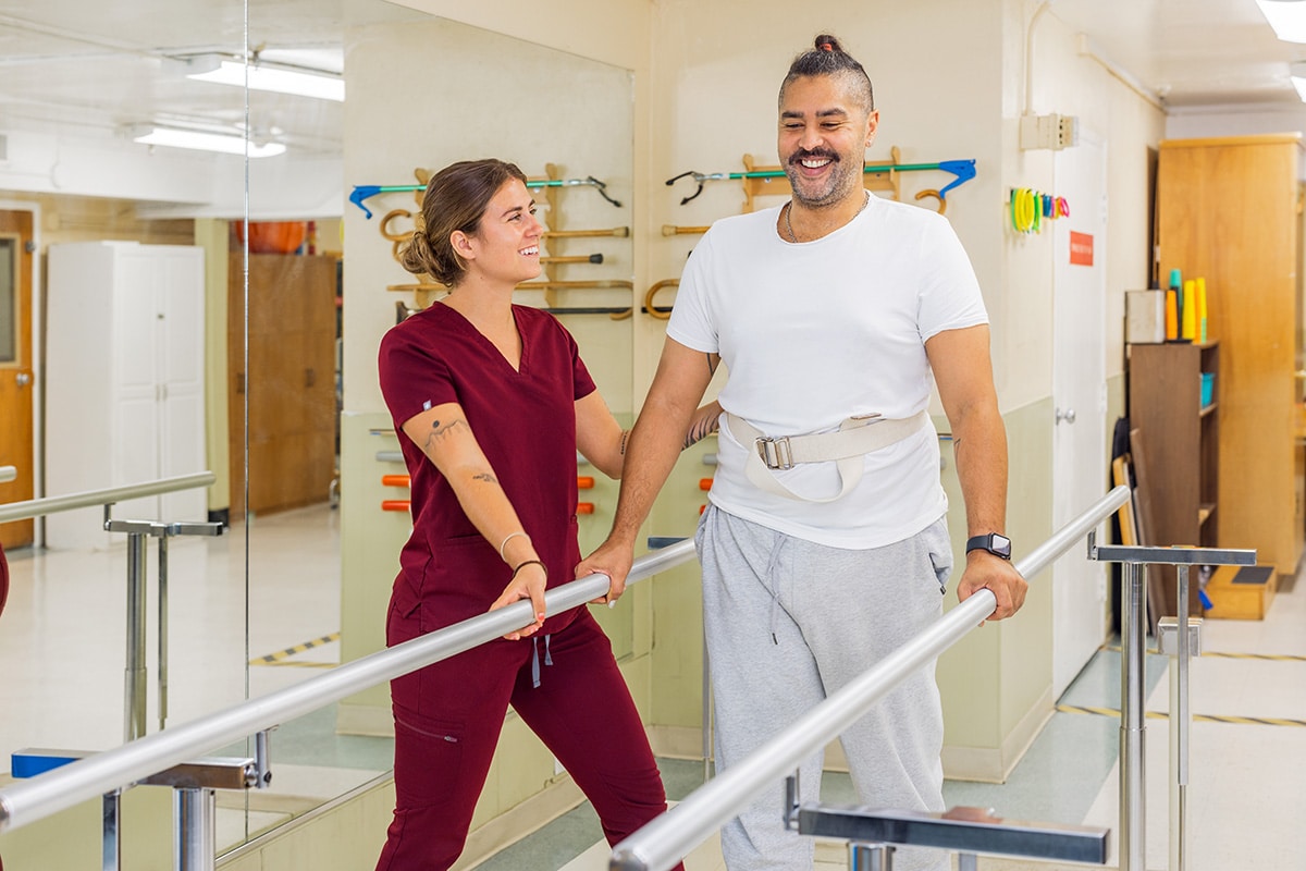 A physical therapist helping a man walk at Medical Hill